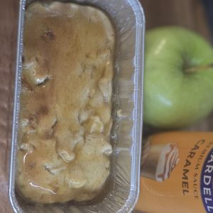 Caramel apple pound cake in a mini loaf pan beside an apple and caramel sauce