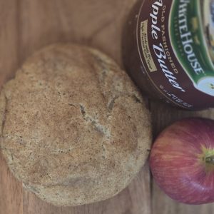 Apple butter snickerdoodle cookie beside apple butter and an apple